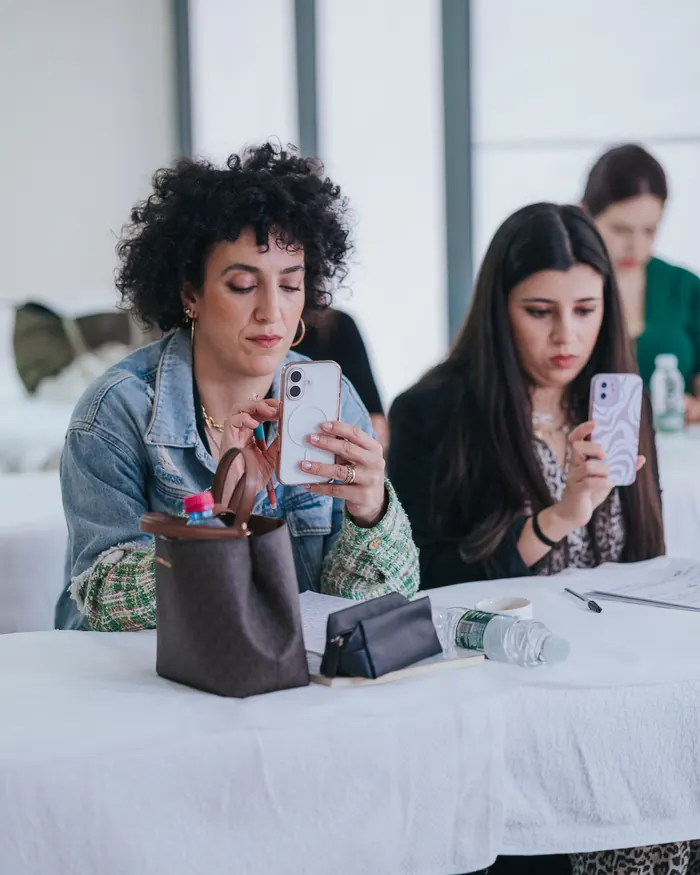 Duas participantes a fotografar com o telemóvel durante um exercício prático.