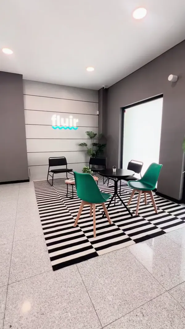 A receção do FluirOffice, com o logótipo Fluir na parede e mesas sobre um tapete às riscas.